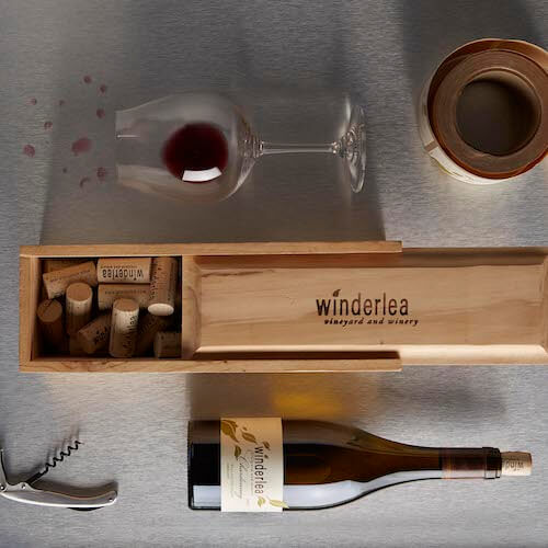Bottle of Winderlea wine, corkscrew, box of corks and a glass of wine